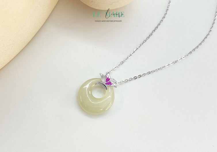 Dây chuyền ngọc bích nữ "Tử Yên" – Nốt trầm của vẻ đẹp an lành BNDC52 Dây chuyền "Tử Yên" không chỉ là món trang sức, mà còn là lời thủ thỉ nhẹ nhàng của tâm hồn – tĩnh tại mà sâu sắc, mềm mại nhưng không kém phần vững chãi. Viên ngọc bích xanh ngọc được đặt giữa trung tâm, được bao bọc bởi họa tiết ánh tím ẩn hiện như cánh hoa chớm nở, gợi hình ảnh yên bình của một buổi hoàng hôn tĩnh lặng nơi vườn xưa.