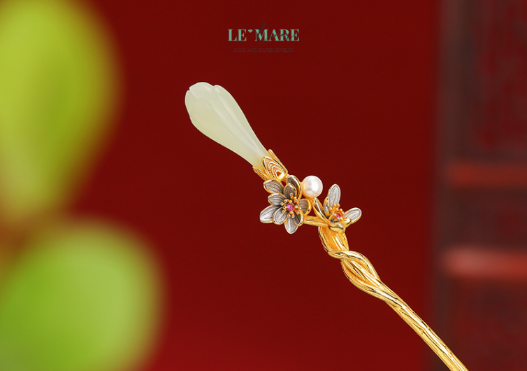 Trâm Cài Tóc Thanh Hoa – Khi nụ hoa ngọc bích chớm nở giữa mái tóc người thiếu nữ BNTC01 Không quá phô trương, trâm cài tóc ngọc bích nữ Thanh Hoa mang dáng hình nhỏ nhắn nhưng đầy khí chất. Phần thân trâm được làm từ bạc thủ công chạm khắc tinh xảo, ôm trọn lấy viên ngọc bích thiên nhiên – như cách một bông hoa ôm lấy nhụy ngọc trong lòng mình.Dưới ánh nắng nhẹ, chiếc trâm cài bạc lấp lánh ánh sáng ngọc xanh, khiến từng lọn tóc cũng như thăng hoa, sống động hơn bao giờ hết. Một vẻ đẹp không ồn ào, nhưng đủ sức níu ánh nhìn.